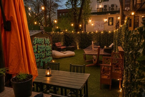 Eine gemütliche Außenveranda mit einem Holztisch und -stühlen, einer Hängematte und Lichterketten.