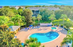 Resort com uma grande piscina, espreguiçadeiras e vegetação exuberante.