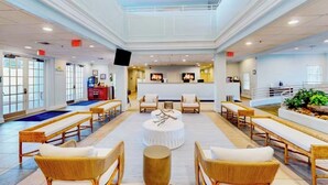A spacious lobby with a reception desk, seating area with wicker chairs and a central round table, and a large window providing natural light. - 3-bedroom 2BA condo near Disney! In a private resort! With beach! Pools!Hot tub! (Davenport)