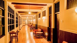 A hotel corridor with wooden floors, seating areas, and a long hallway with windows and doors. - Gimanhala Hotel (Dambulla)