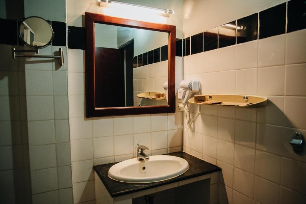 Een badkamer met een wastafel, spiegel en handdoekhouder.