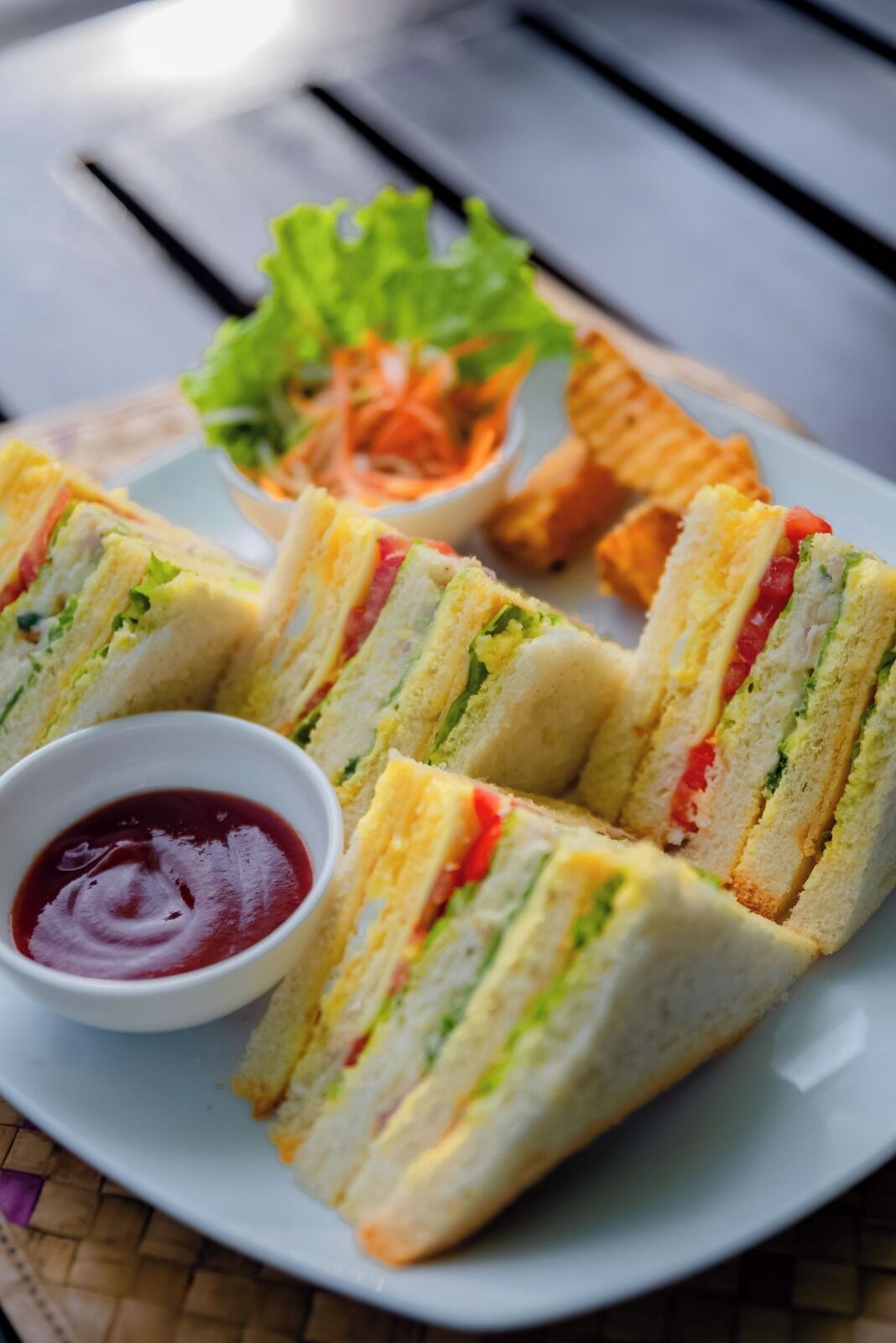 Un plato con sándwiches, una ensalada pequeña y un recipiente con salsa.