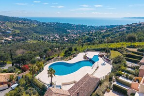 A swimming pool with a curved design, surrounded by well-maintained gardens and a view of a coastal town. - 1 bedroom apt - Sea View & Pool, Roquebrune-Sur-Argens, France (Roquebrune-Sur-Argens)