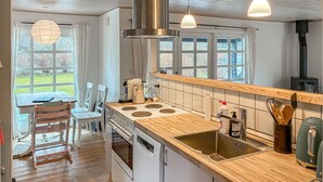 Una cocina con encimera de madera, electrodomésticos de acero inoxidable y vistas al exterior a través de amplios ventanales.