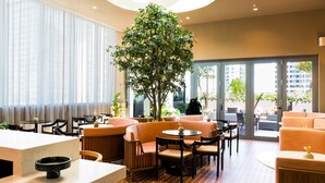 Een hotel lobby met zithoeken, een receptiebalie en een grote boom.
