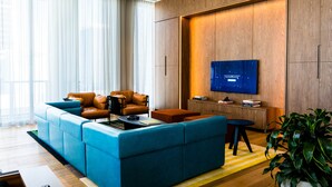 Een moderne woonkamer met een modulaire bank, lederen fauteuils, een flatscreen televisie en een houten accentmuur.
