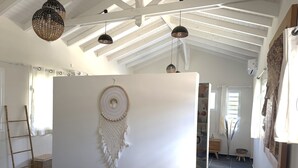 Quarto com teto alto, parede branca com um sonho capturado, escada e cesta.
