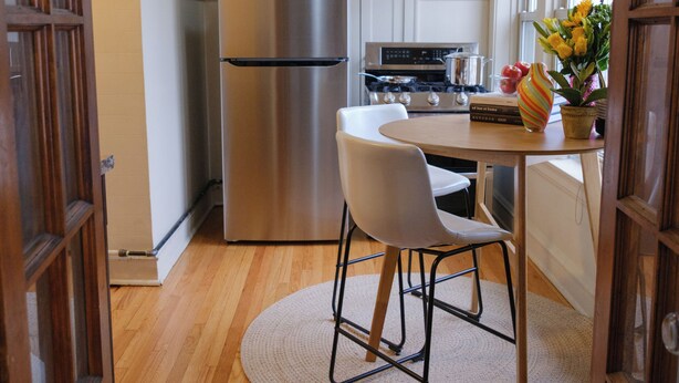 Une cuisine équipée d’un réfrigérateur, d’une cuisinière et d’une table à manger avec des chaises.