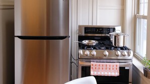 Une cuisine équipée d’un réfrigérateur en acier inoxydable, d’une cuisinière et d’une table à manger blanche.