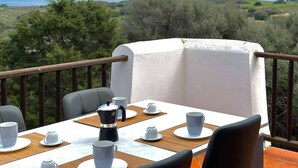 Ein Balkon mit einem für Tee gedeckten Tisch, mit Blick auf eine Küstenlandschaft.