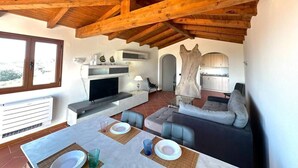 Ein modernes Wohnzimmer mit Kamin, Sofa, Esstisch und Küchenzeile.