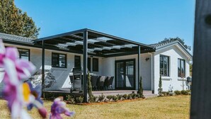 Une maison moderne dotée d’un patio couvert, d’une pelouse et offrant une vue sur un ciel dégagé.