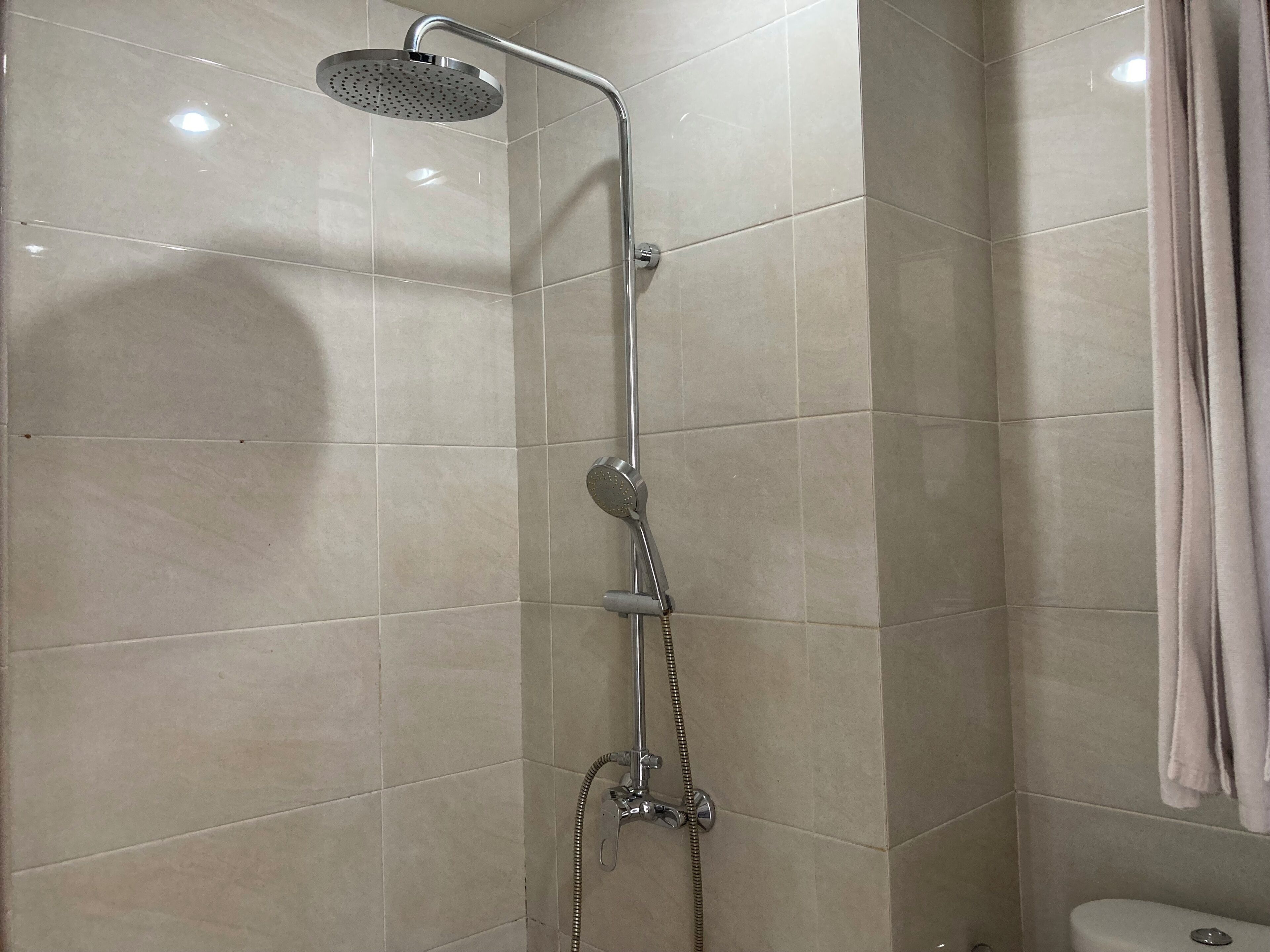 A shower with a handheld showerhead and a wall-mounted faucet.