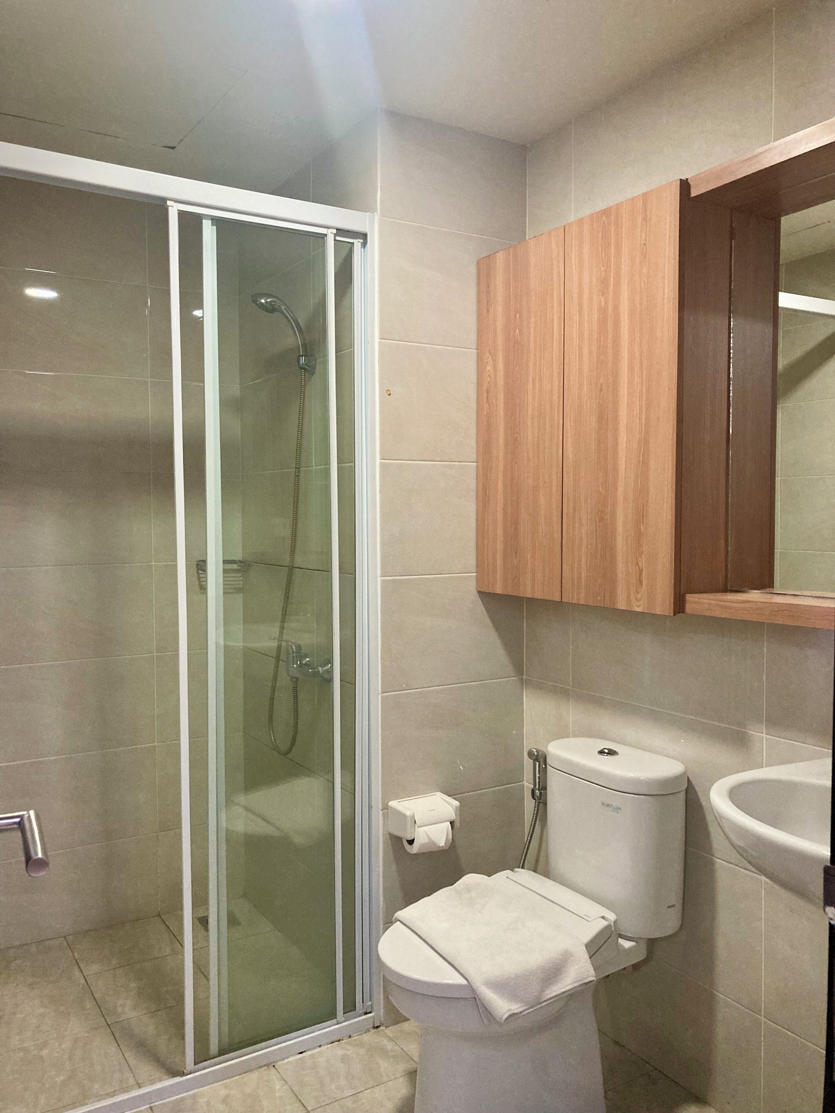 Ein Badezimmer mit Duschkabine, Toilette, Waschbecken und Holzschrank.