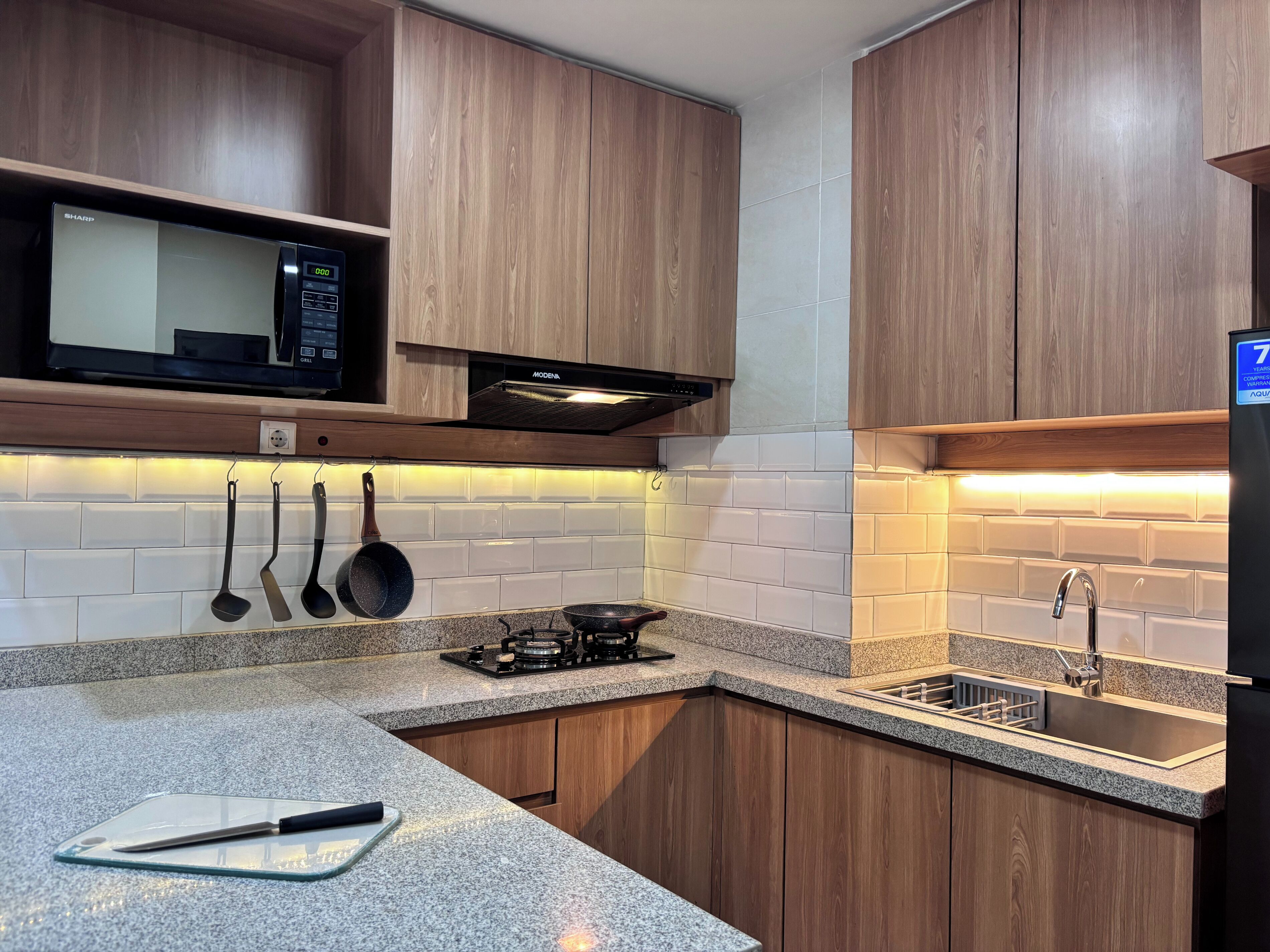 Een moderne keuken met houten kastjes, een magnetron, een gasfornuis en een spoelbak.