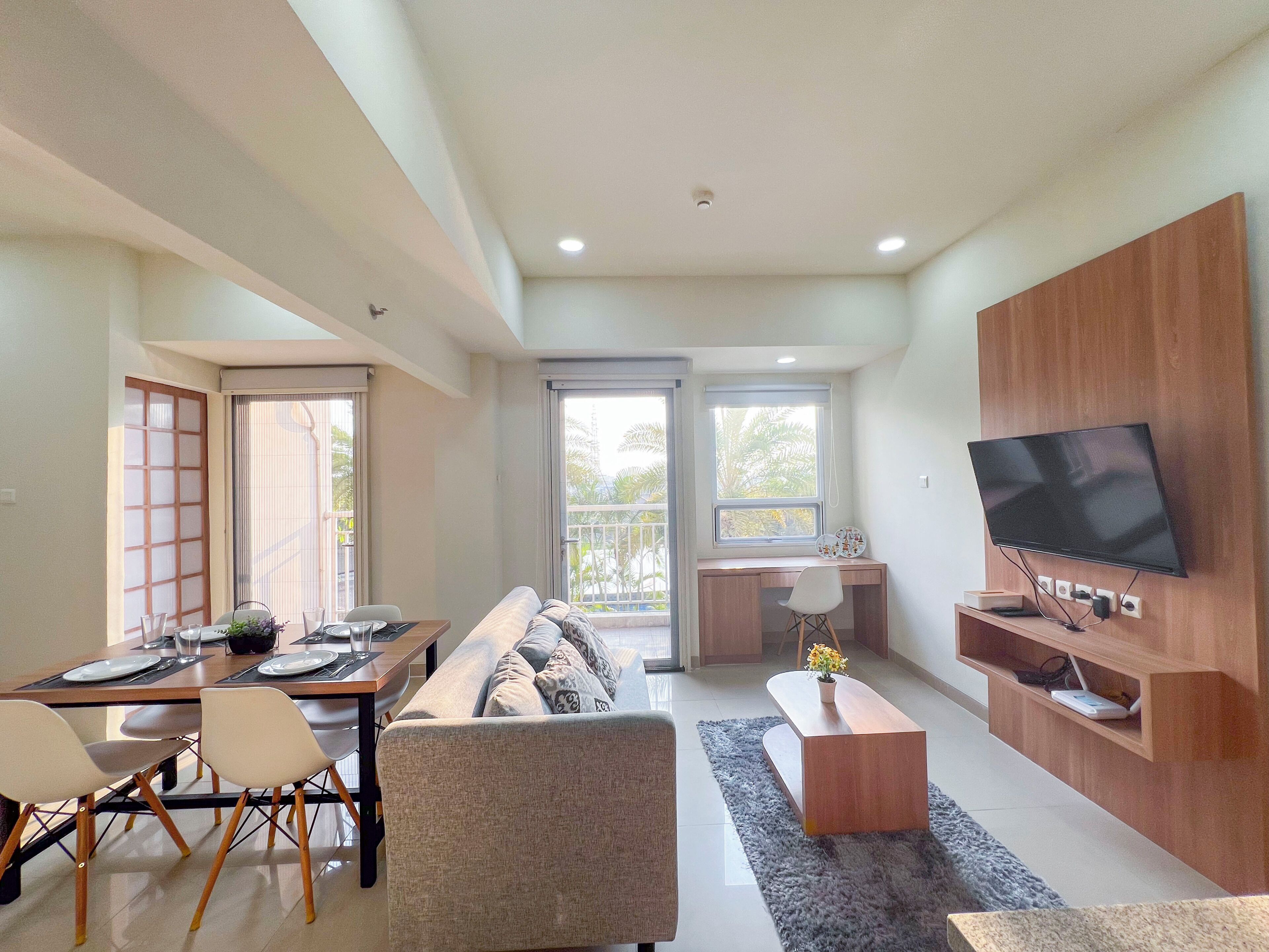 A modern living room with a sofa, dining table, and TV.