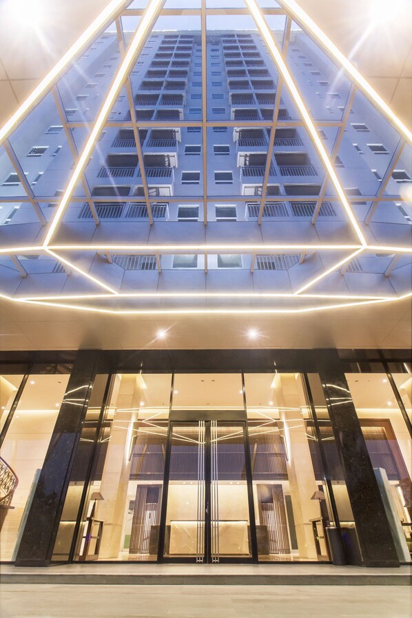 Un edificio moderno con techo de vidrio geométrico, ventanas amplias y suelo reflectante.