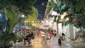 An outdoor café with tables and chairs, surrounded by greenery and string lights. - Merakey Golf Residence  (Cikarang)