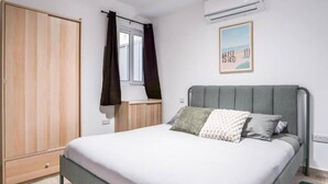 A bedroom with a bed, a wardrobe, a window with curtains, an air conditioner, and a framed picture on the wall. - Ground Floor Maisonette With Communal Pool in Qala (Qala)