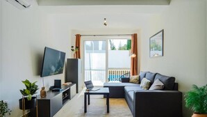 A modern living room with a sofa, a flat-screen TV, a coffee table, and a potted plant. - Ground Floor Maisonette With Communal Pool in Qala (Qala)