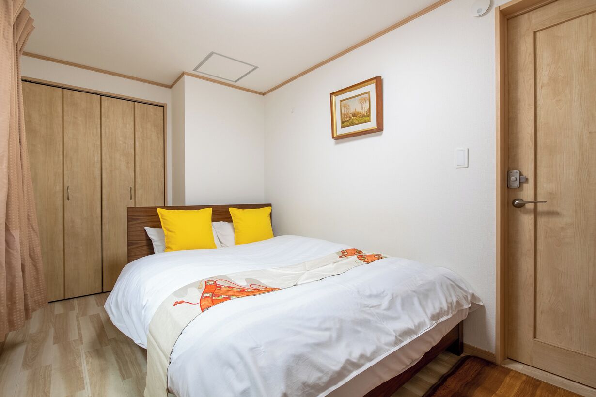 A bedroom with a bed, wooden wardrobe, and a door.