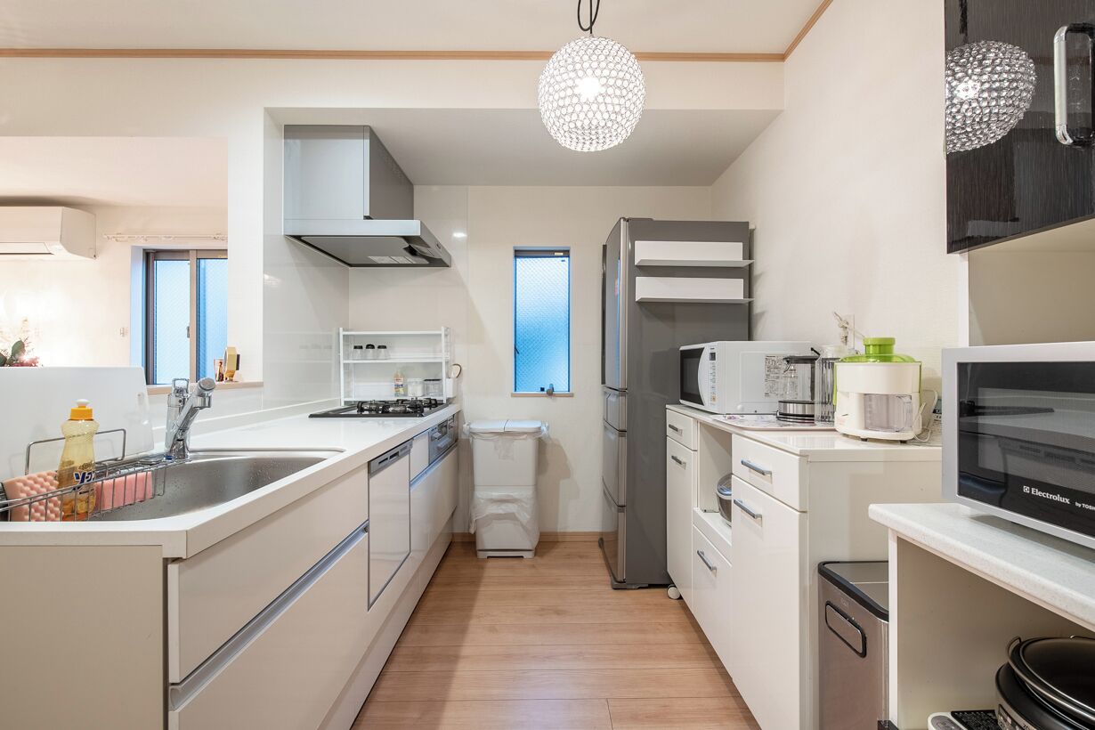 A modern kitchen with white cabinetry, a stainless steel refrigerator, a microwave, and a sink.