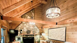 A cozy log cabin interior with a stone fireplace, leather furniture, and a map on the wall. - Sundance Retreat - Pet Friendly Mountaintop Cabin (Sevierville)