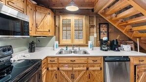 A kitchen with wooden cabinets, a stove, a sink, and a dishwasher. - Sundance Retreat - Pet Friendly Mountaintop Cabin (Sevierville)