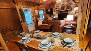 A wooden dining table set with plates, glasses, and cutlery, surrounded by chairs. - Sundance Retreat - Pet Friendly Mountaintop Cabin (Sevierville)