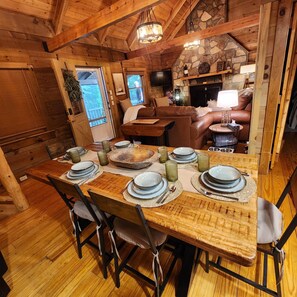 A wooden dining table set with plates, glasses, and cutlery, surrounded by chairs. - Sundance Retreat - Pet Friendly Mountaintop Cabin (Sevierville)