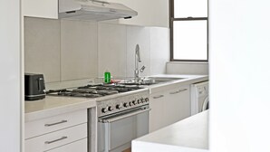 A kitchen with a stove, oven, sink, and a window. - Sea View Ocean Facing Spacious 1 Bedroom Apartment (Cape Town)