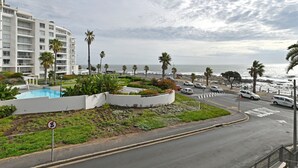 A coastal hotel with a pool, palm trees, and a view of the ocean. - Sea View Ocean Facing Spacious 1 Bedroom Apartment (Cape Town)