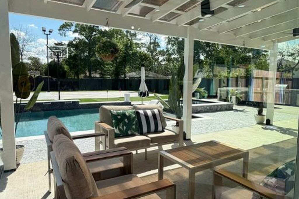 Un espacio al aire libre cubierto con piscina, mobiliario y plantas en macetas.