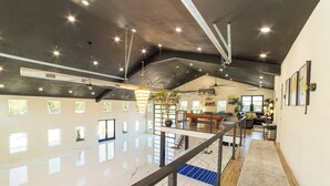 A spacious interior with a high ceiling, large windows, and a mezzanine level. - Sleeps 30, Private Ranch, 15 acre, Pool, Pond, sauna, pikleball court near DFW (Corsicana)