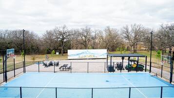 An outdoor basketball court with a fence, a bench, and a golf cart.