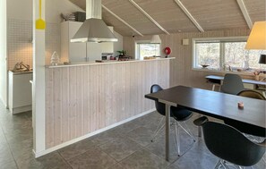 A modern kitchen with a central island, a dining area with a table and chairs, and a window providing a view of the outdoors. - 2 bedroom stunning home in Vig (Vig)
