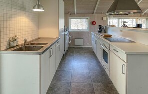 A kitchen with a sink, stove, and a window with a view of trees. - 2 bedroom stunning home in Vig (Vig)