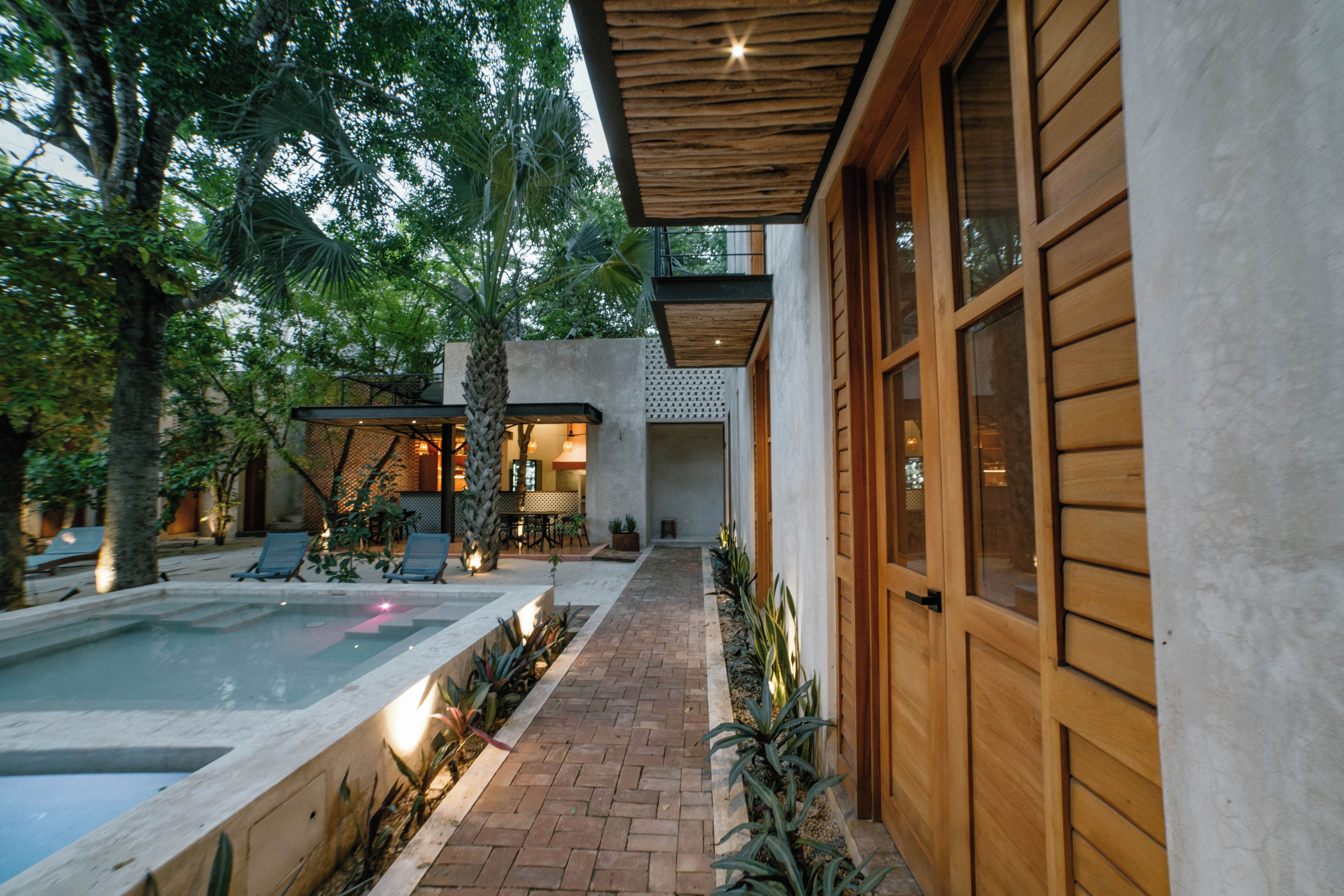 Un espace piscine extérieur moderne, doté de chaises longues et d’une terrasse en bois.