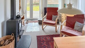 A cozy room with a fireplace, two red chairs, a wooden table, and a view of the outdoors. - Awesome home in Kalundborg with WiFi (Kalundborg)