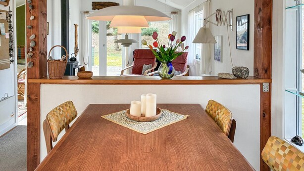 A dining area with a wooden table, three chairs, a vase with flowers, and a lamp. - Awesome home in Kalundborg with WiFi (Kalundborg)