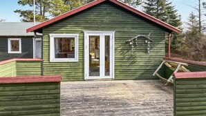 A green wooden cabin with a red roof, a front door, and a small porch area. - Awesome home in Kalundborg with WiFi (Kalundborg)