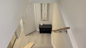 Un escalier avec une rampe en bois, une pancarte de bienvenue et un banc au bas de l’escalier.