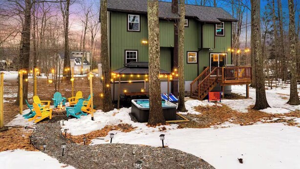A two-story house with a deck, surrounded by trees and a hot tub. - Hot Tub, Jungle Gym, Fire Pit - Private Cabin Gem! (Tobyhanna)