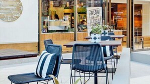 An outdoor seating area with chairs and tables, a clock on the wall, and a storefront with a sign reading 'PROVIDORE.' - Hawks Nest Hideaway | Spa, BBQ, Bikes & Pool Table (Hawks Nest)