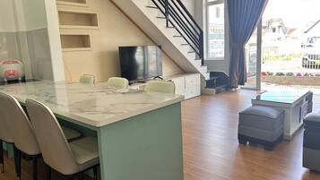 Un soggiorno moderno con isola cucina in marmo, una scala e vista sull'esterno.