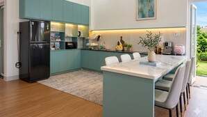 Una cocina moderna con armarios verde azulado, una isla central y un refrigerador.