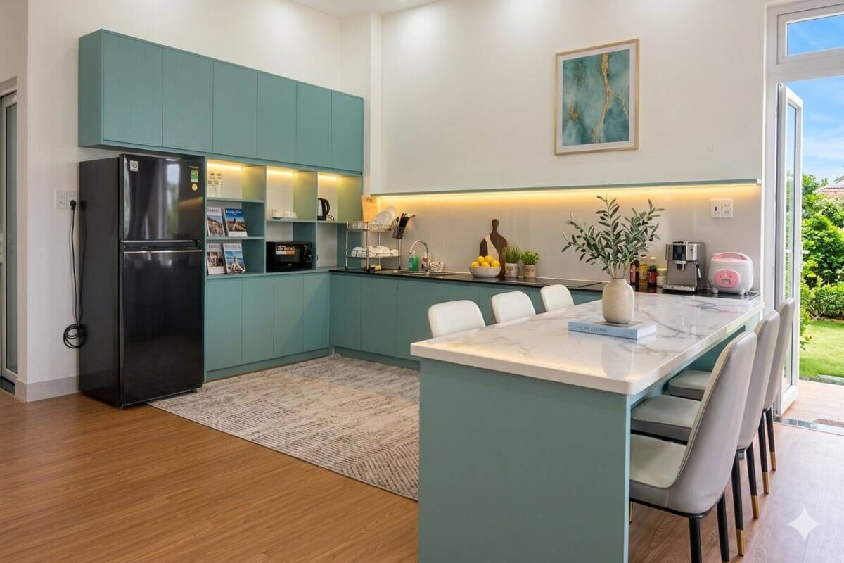 Una cocina moderna con armarios verde azulado, una isla central y un refrigerador.