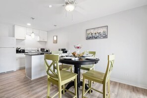 A modern kitchen with white cabinets, a dining table with four chairs, and a ceiling fan. - Charming 2 BR near Deep Ellum (Dallas)