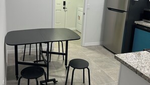Et køkken med spisebord, stole, køleskab og opvaskemaskine.