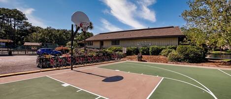 Ein Basketballplatz im Freien, im Hintergrund ein Gebäude mit der Aufschrift 'Island Club Tennis & Fitness Center'.
